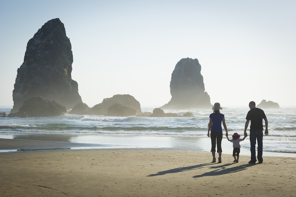 Family on Oregon coast looking at large rocks