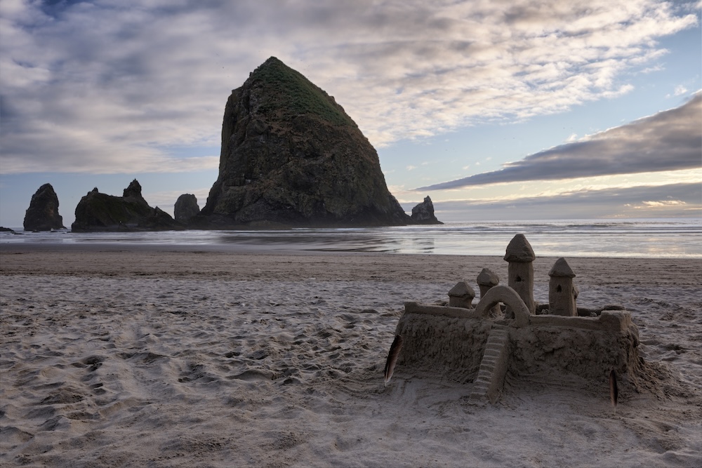 sandcastle on beach in Cannon Beach, Oregon with Haystack Rock in background