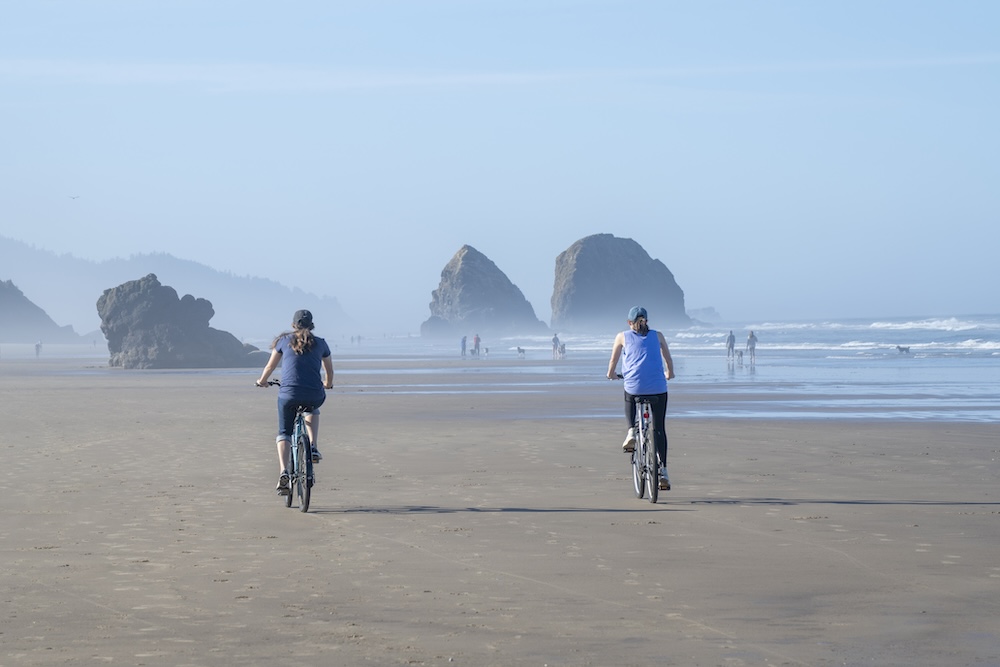 Two young women biking on Cannon Beach